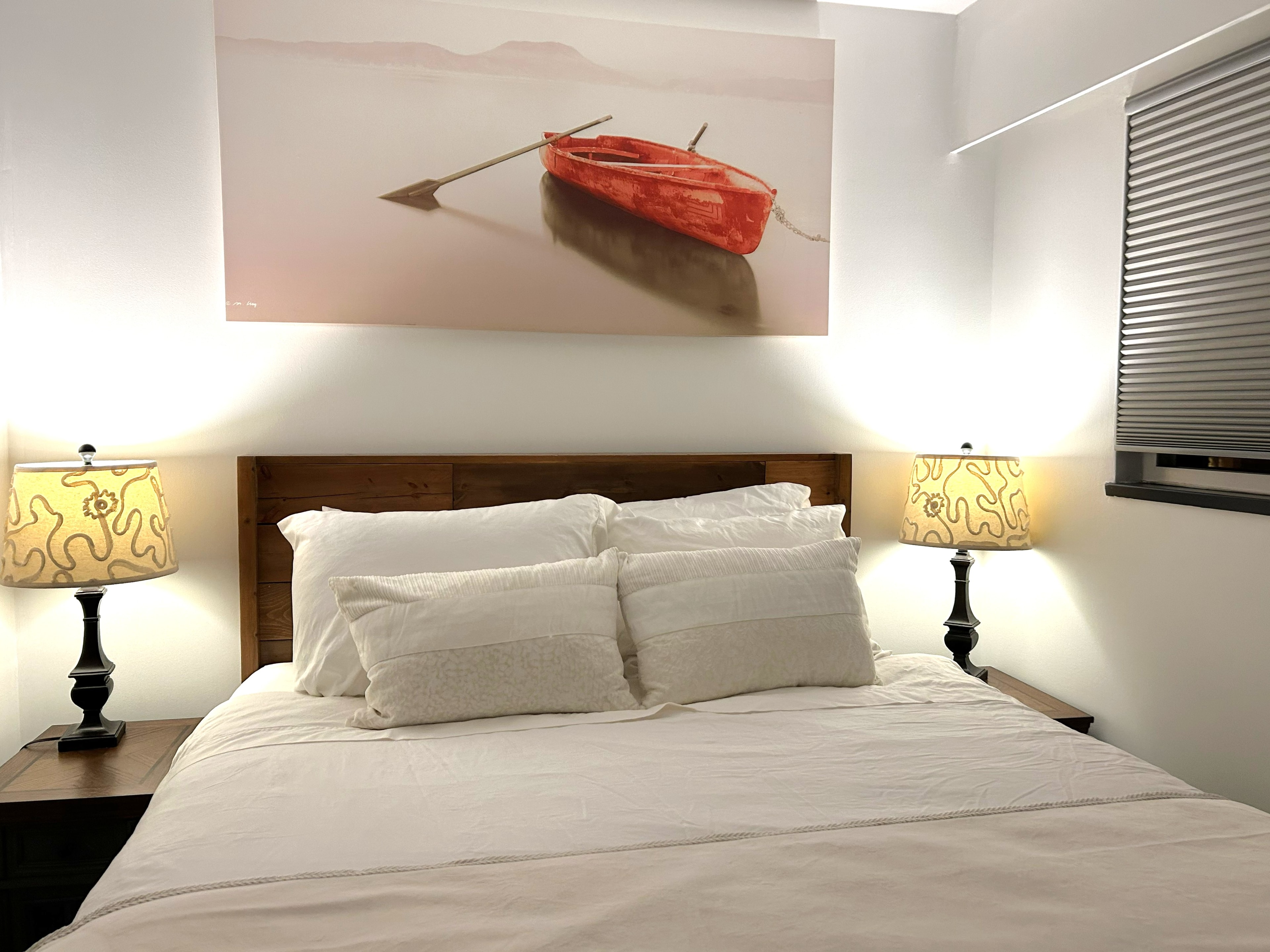 Beatrice Street suite queen bedroom with wooden headboard and warm bedside lamps