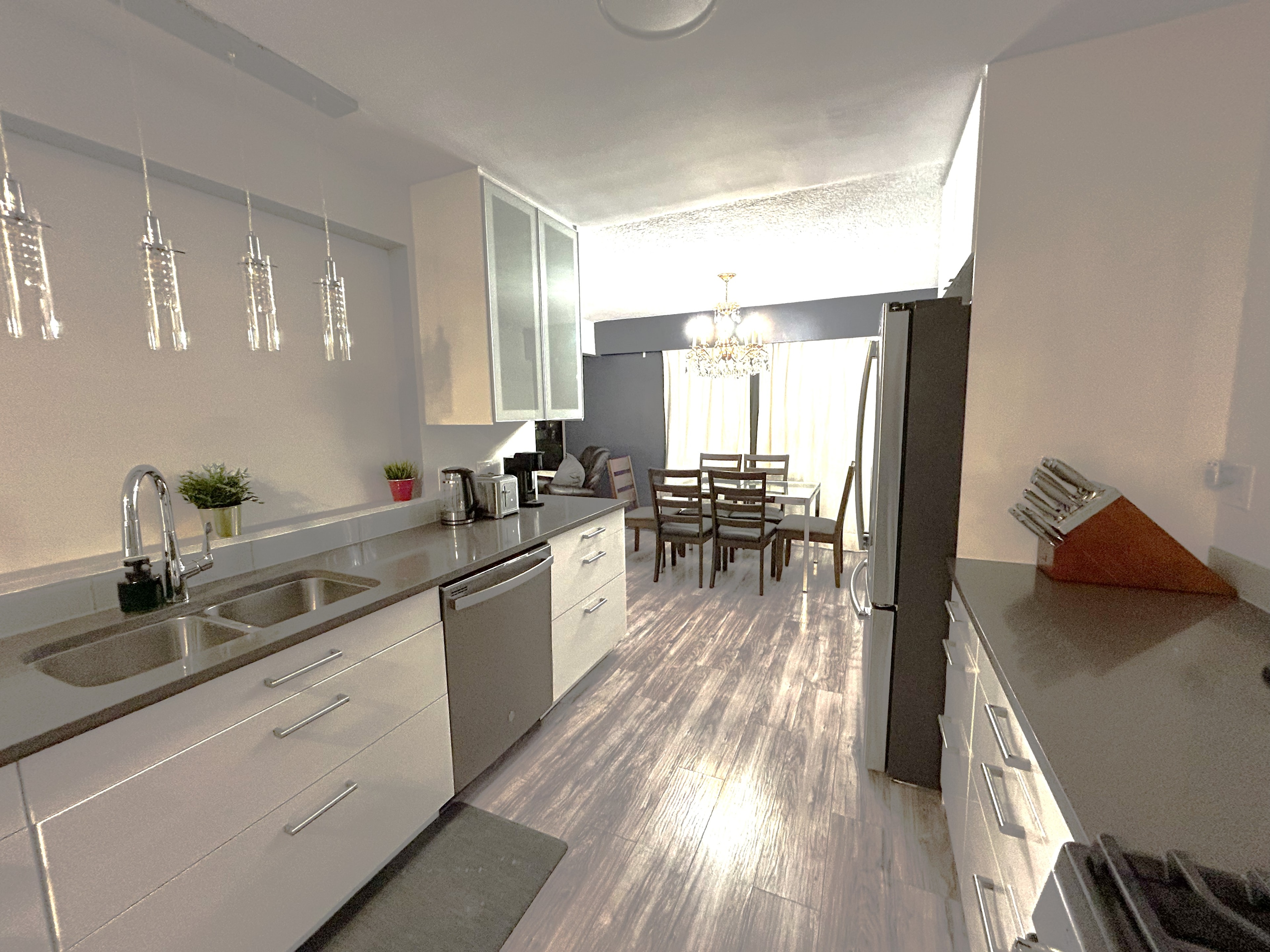 Beatrice Street suite kitchen with quartz countertops, stainless appliances, and dining area with chandelier